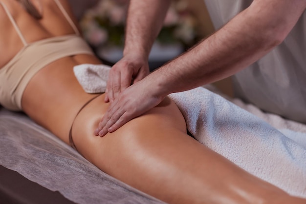 Foto masaje anticelulítico en el salón de spa el masajista masajea glúteos muslos y piernas tratamiento relajante adelgazamiento y remodelación cuerpo y piel sanos cuidado del amor propio