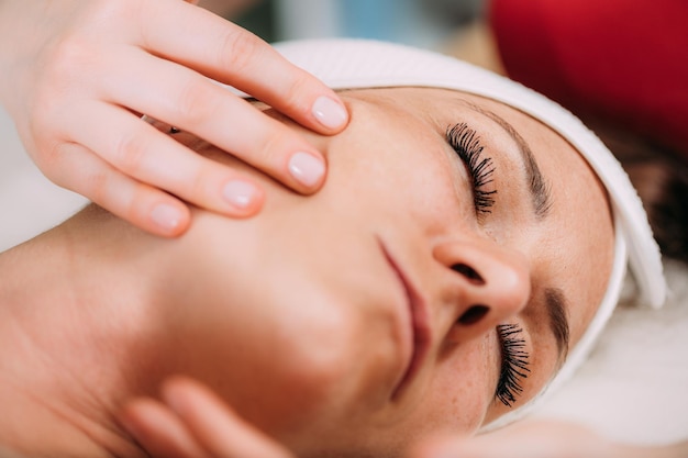 Masaje de estiramiento facial hermosa mujer recibiendo masaje de estiramiento facial en un salón de belleza