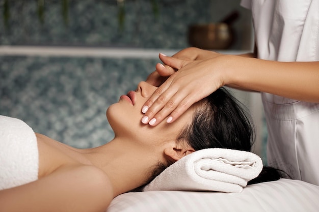 Masaje facial anti-envejecimiento. Mujer recibiendo masajes de masajista en el salón Spa.