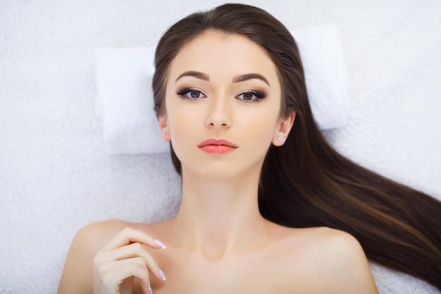 Masaje facial Hermosa joven relajante con masaje de manos en el salón de belleza spa