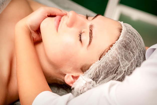 Foto masaje facial manos de un masajista masajeando el cuello de una joven mujer caucásica en un salón de spa el concepto de masaje de salud