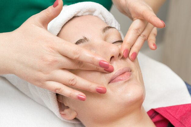 Masaje facial Mujer joven recibiendo tratamiento de masaje spa en el salón de belleza spa Spa cuidado de la piel