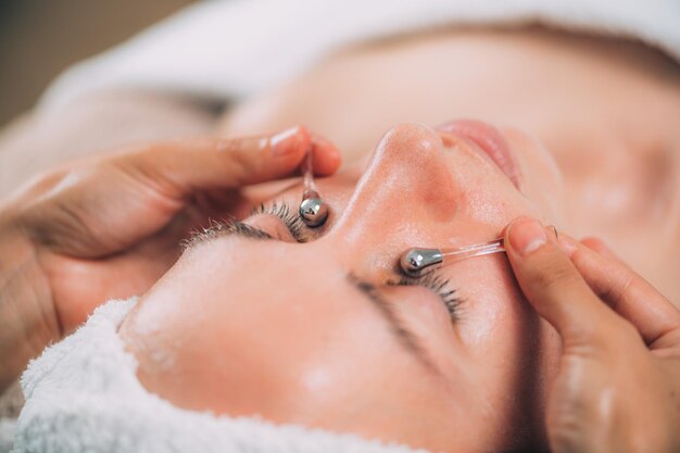 Masaje facial con palillos de drenaje linfático para las ojeras debajo de los ojos