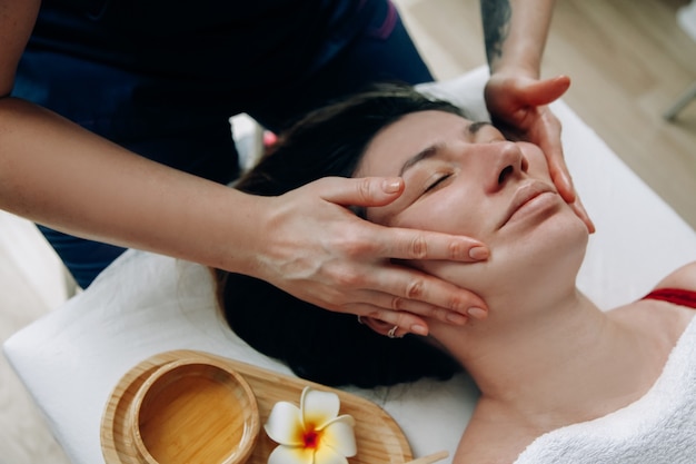 Masaje facial Primer plano de una cara de mujer Terapeuta de masaje haciendo masaje facial a una persona