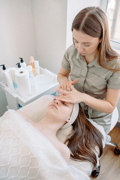 Masaje facial Primer plano de una mujer joven que recibe un masaje de spa en un salón de belleza Cuidado de la piel y el cuerpo Spa Cosmetología facial foto vertical