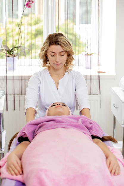 Masaje facial Primer plano de una mujer joven que recibe un tratamiento de masaje spa en el salón de spa de belleza Cuidado de la piel y el cuerpo Spa Tratamiento de belleza facial Cosmetología