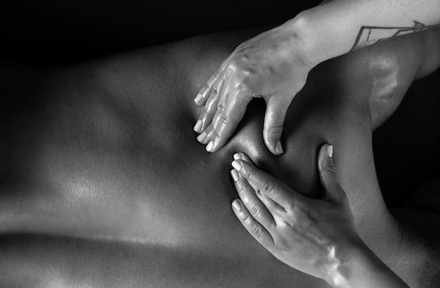 Masaje de manos de mujeres en primer plano Fisioterapeuta masajeando el hombro y el cuello de un atleta masculino