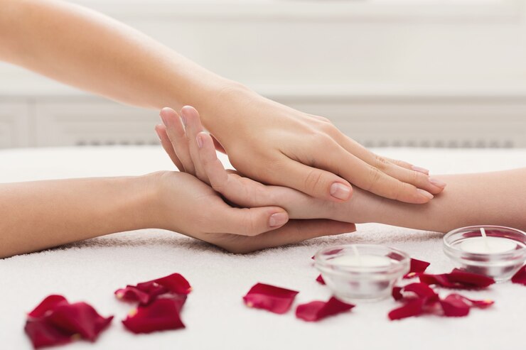 Masaje de manos en salón de belleza. Manicura, uñas y cuidado de la piel en el spa en una toalla blanca con pétalos de rosa