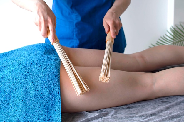 Masaje con palos de bambú. Acción. Masaje con escobas de bambú para la celulitis. Palos de bambú para ayudar con la envoltura y el masaje de drenaje más efectivo. Tratamientos de spa con masaje.