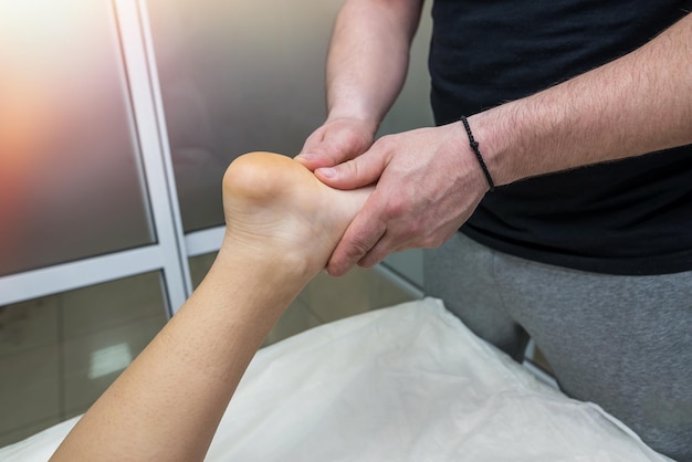 Masaje de pies de cerca Un terapeuta de masaje masculino masajea el pie de una niña