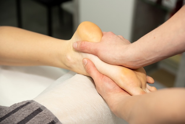 Masaje de pies en el paciente. El médico hace el masaje de los pies, talones y dedos en las piernas.