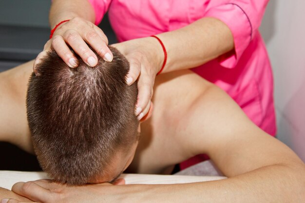 Foto masaje terapéutico profesional de cuello y cabeza, el atleta en un procedimiento de recuperación del dolor en la sala de masajes