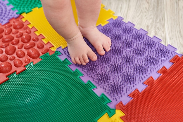 Masajeador de pies Niño caminando sobre una colchoneta de masaje ortopédico Tratamiento y prevención del pie plano en niños