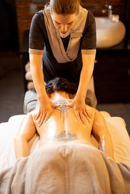 Masajista aplica masaje de relajación a una mujer en el salón de spa