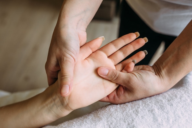 El masajista da masaje a la mano femenina en el spa