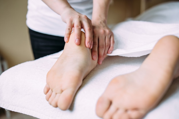 El masajista da un masaje a los pies femeninos en el spa