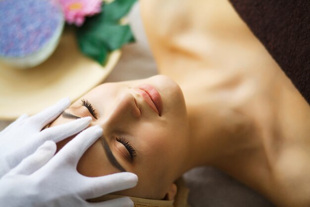 Masajista haciendo masaje la cabeza de una mujer en el salón de spa