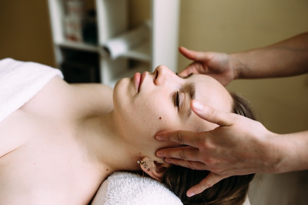 Masajista haciendo masaje en la cara de una mujer en el spa