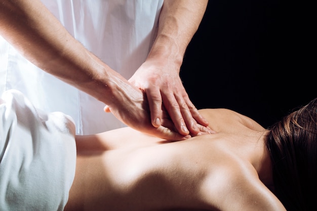 Masajista haciendo masaje en el cuerpo de la mujer en el salón de spa. Mujer en el salón de spa, masaje.