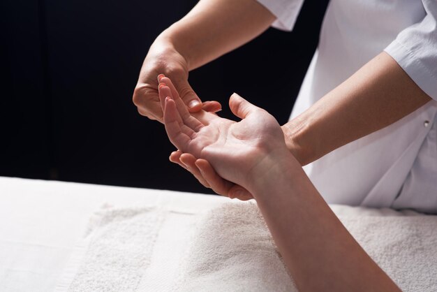 Masajista haciendo masaje de manos con aceite en el salón de spa Procedimientos de spa Concepto de cuidado corporal Vista de cierre