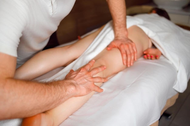 Masajista haciendo masaje de piernas a mujer Tratamientos de spa