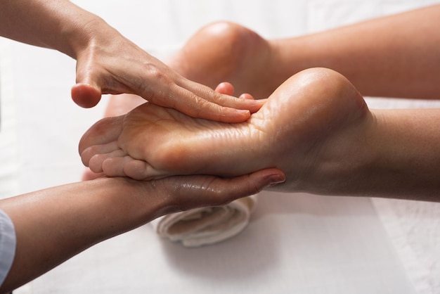 Masajista haciendo masaje de pies con aceite en el salón de spa Procedimientos de spa Concepto de cuidado corporal Vista de cierre