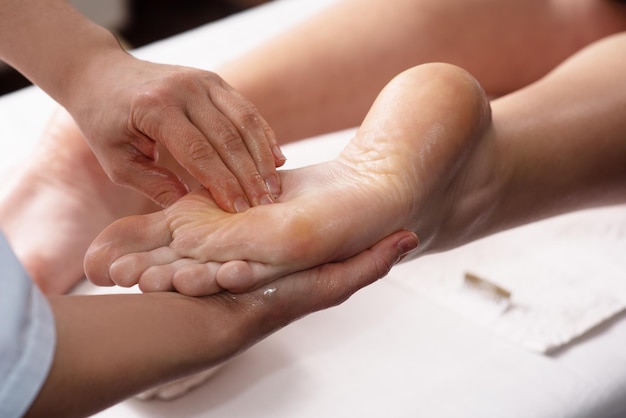 Masajista haciendo masaje de pies con aceite en el salón de spa Procedimientos de spa Concepto de cuidado corporal Vista de cierre