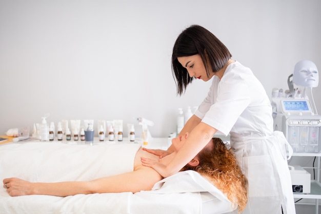 Masajista masajeando los hombros de la mujer en el centro de belleza.