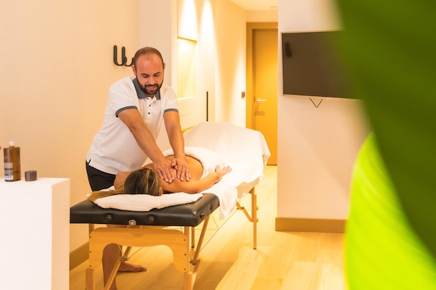 Masajista masculino realizando un masaje en la mesa a un cliente