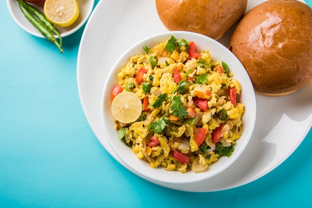 Masala Anda Bhurji oder würziges indisches Rührei mit geröstetem Brot oder Brötchen oder Pav, beliebtes Streetfood in Mumbai. Serviert in weißem Geschirr über stimmungsvollem Hintergrund. selektiver Fokus