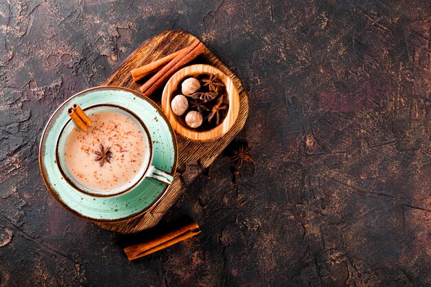 Masala chá indiano tradicional chá com leite e especiarias em uma xícara no fundo escuro vista superior grátis