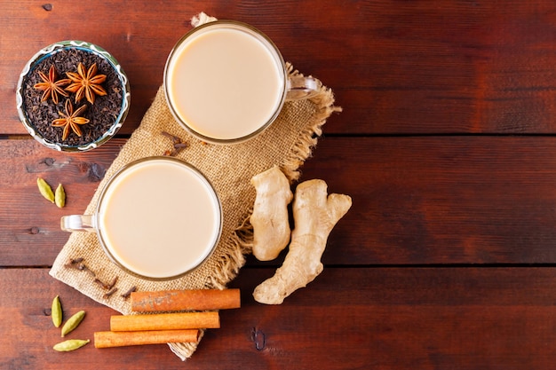 Masala Chai Tee auf Sackleinen. Traditionelles indisches Getränk - Masala-Tee mit Gewürzen auf einem hölzernen Hintergrund.