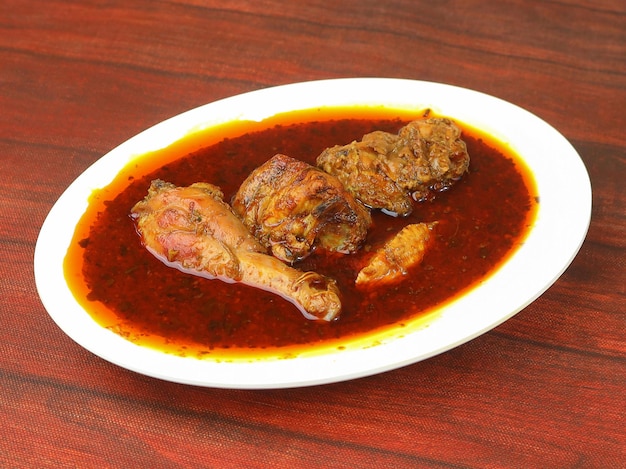 Masala de frango feito de especiarias indianas servido em uma tigela sobre um foco seletivo de fundo rústico de madeira