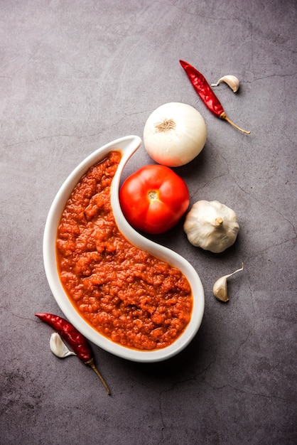 Foto masala de tomate de cebola ou purê para molho indiano, servido em uma tigela com tamatar cru, pays e lehsun e pimenta vermelha,