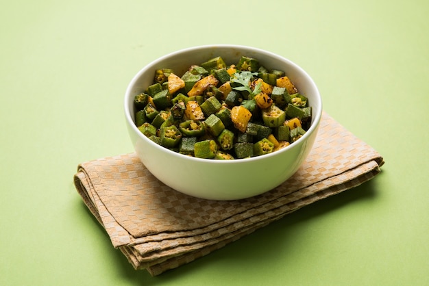 Masala Sabji O Sabzi al estilo indio de Bhindi O Okra frito, también conocido como Ladyfinger, servido en un cuenco sobre un fondo de mal humor. enfoque selectivo