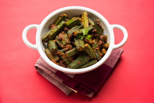 Masala Sabji ODER Sabzi nach indischer Art mit gebratenem Bhindi ODER Okra, auch bekannt als Ladyfinger, serviert in einer Schüssel über stimmungsvollem Hintergrund. selektiver Fokus