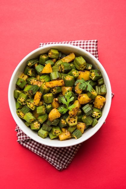 Masala Sabji ODER Sabzi nach indischer Art mit gebratenem Bhindi ODER Okra, auch bekannt als Ladyfinger, serviert in einer Schüssel über stimmungsvollem Hintergrund. selektiver Fokus