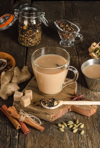 Masala-Tee mit Gewürzen auf einem hölzernen Hintergrund, ein wärmendes Getränk aus Indien
