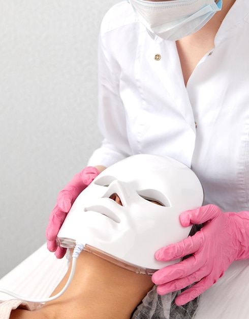 Máscara antienvejecimiento de luz LED para el cuidado de la piel facial en un spa a cámara lenta Una mujer yace en un sofá con una máscara especial Tecnologías modernas de belleza y salud