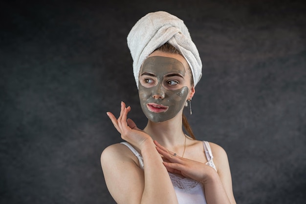 Máscara de arcilla de belleza verde en el rostro femenino aislado en negro
