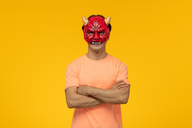 Máscara aterradora joven chico aterrador con las manos cruzadas en máscara roja aterradora