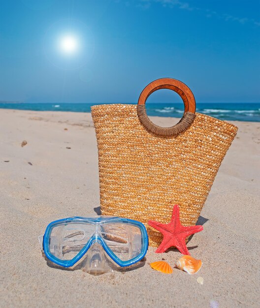 Máscara de buceo con bolsa de paja y estrellas de mar en la playa