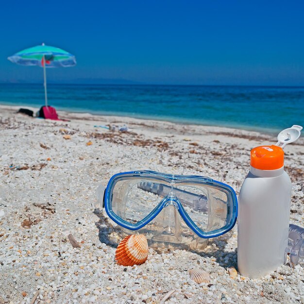 Máscara de buceo y bronceador en la playa.