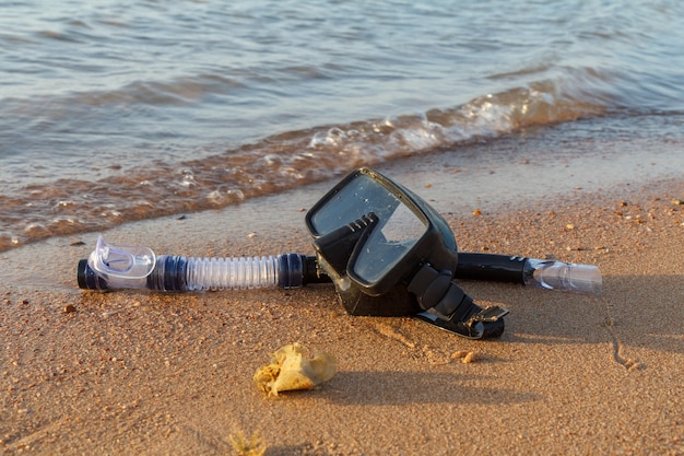 Máscara de buceo y snorkel para profesionales en arena de mar con mar en superficie