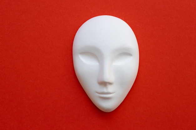 Máscara de cerámica blanca sobre fondo rojo.
