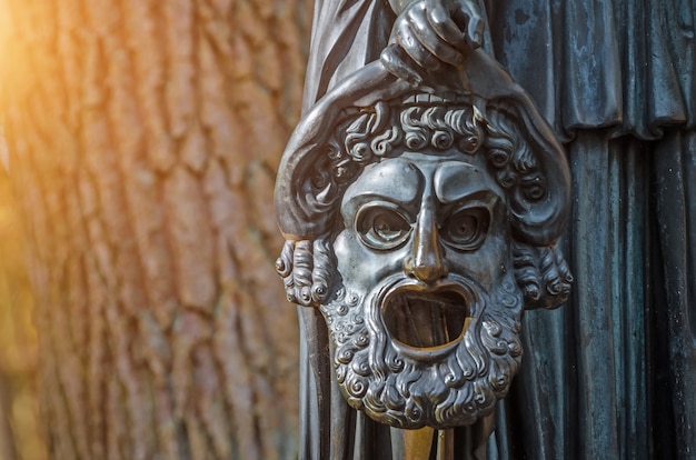 Máscara chorosa de uma escultura de cobre em um parque florestal