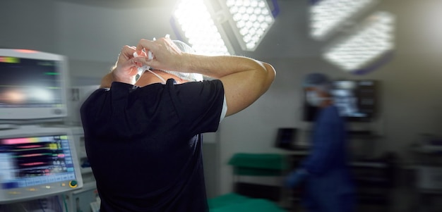 Máscara de corbata de cirujano en la sala de operaciones del hospital o en una clínica ocupada para la salud médica o protección en la sala de emergencias La espalda del médico para atar la gorra o la preparación para la cirugía en trajes de seguridad para el hombre