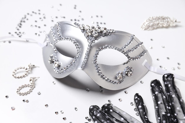 Máscara de carnaval e joias em fundo branco fechadas