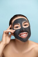 Máscara de cuidados com a pele de rosto de mulher de beleza retrato de uma mulher bonita com uma máscara preta