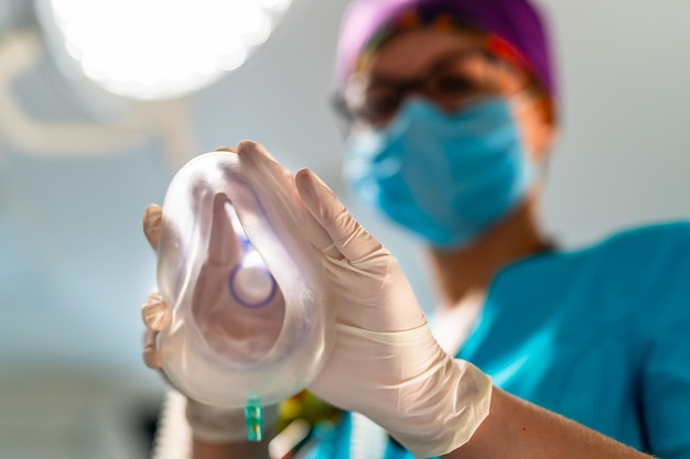 Máscara de oxigênio dos olhos de um paciente. Anestesiologista feminina em esfrega colocando máscara anestésica em uma câmera.